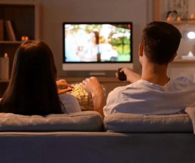 Mladý pár s popcornem sledující televizi