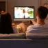 Mladý pár s popcornem sledující televizi