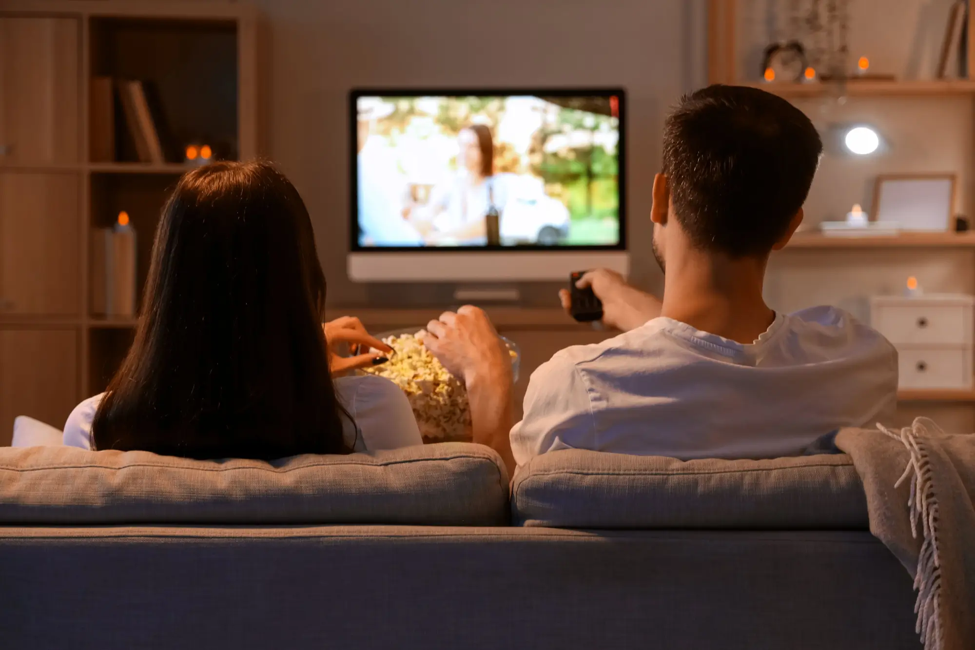 Mladý pár s popcornem sledující televizi