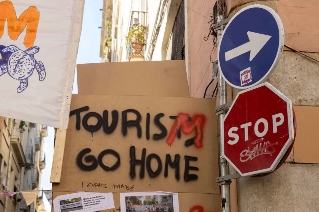 - SportDeník Transparent s nápisem „Tourists go home“ umístěný na ulici mezi dopravními značkami.