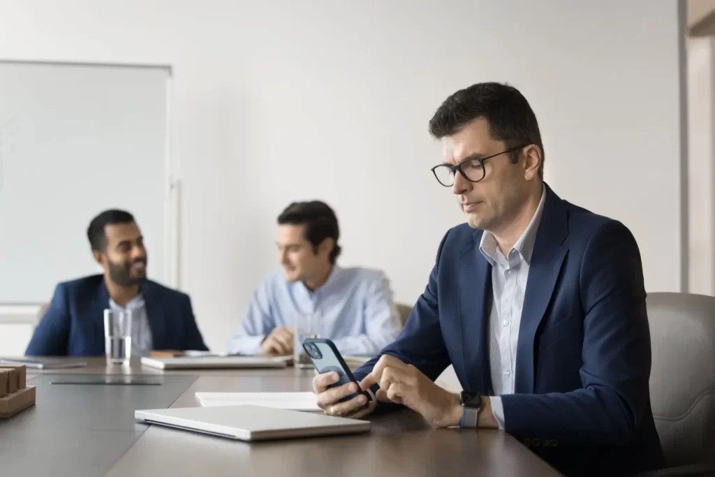 Shutterstock_2540974589 - SportDeník Muže na pracovní poradě koukající do telefonu