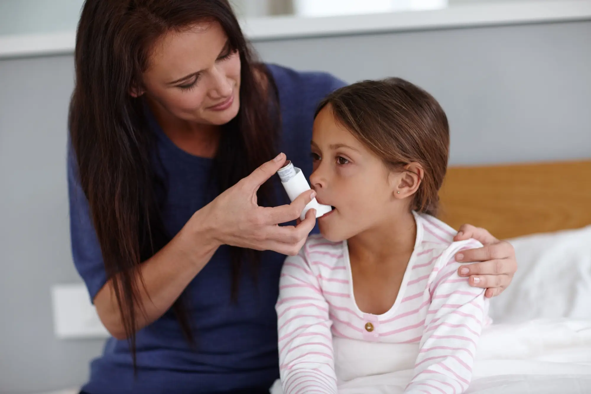 Matka pomáhá dceři používat inhalátor při astmatu