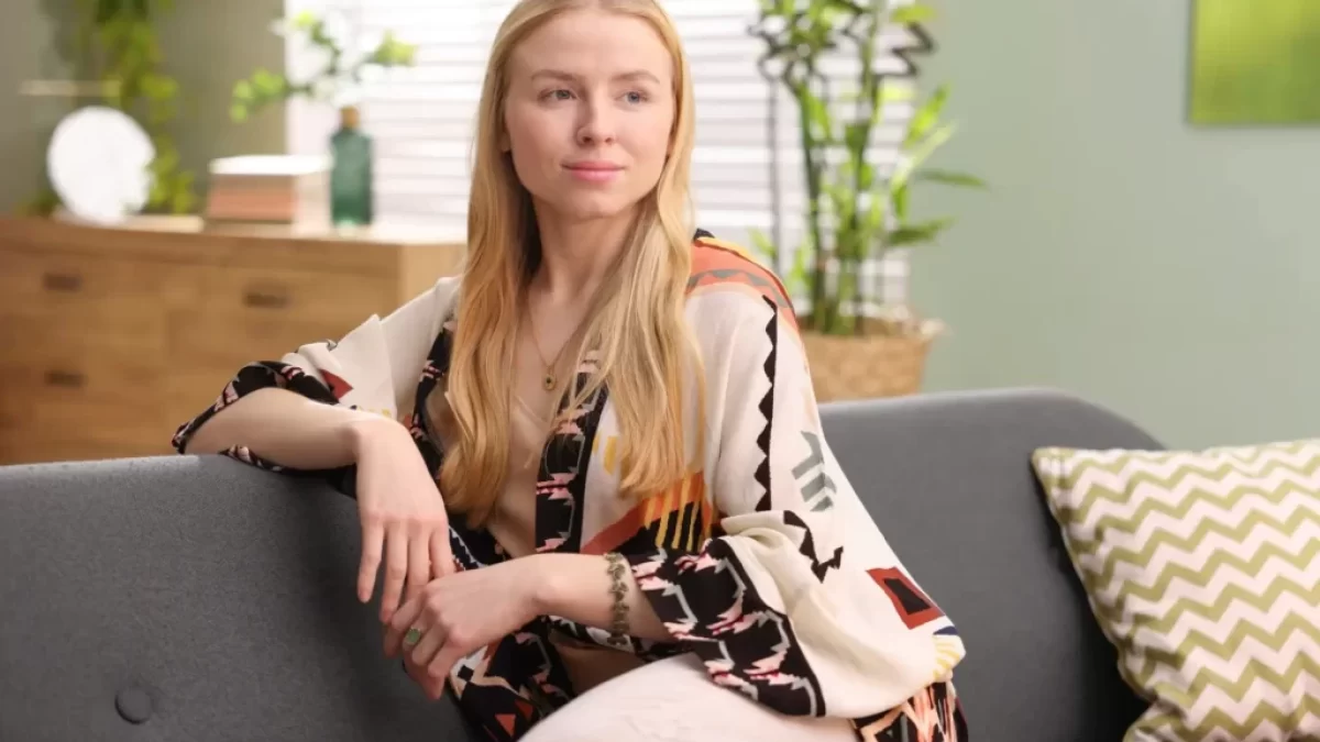 Žena sedící na gauči s rostlinami v pozadí