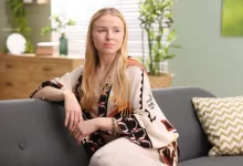 Žena sedící na gauči s rostlinami v pozadí