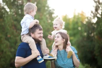 Táta a máma na procházce s dětmi za krkem