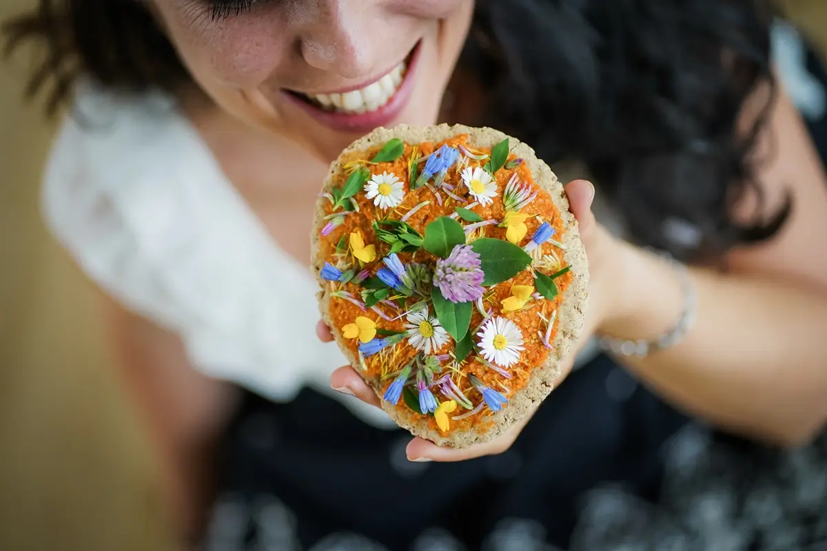 Vegan 2 - SportDeník Mladá žena se usmívá a chystá se zakousnout do zdravější alternativy pizzy.