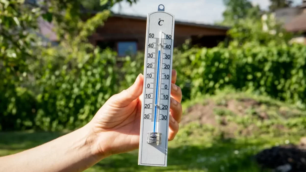 teploměr v ruce zobrazující teplotu 30 stupňů
