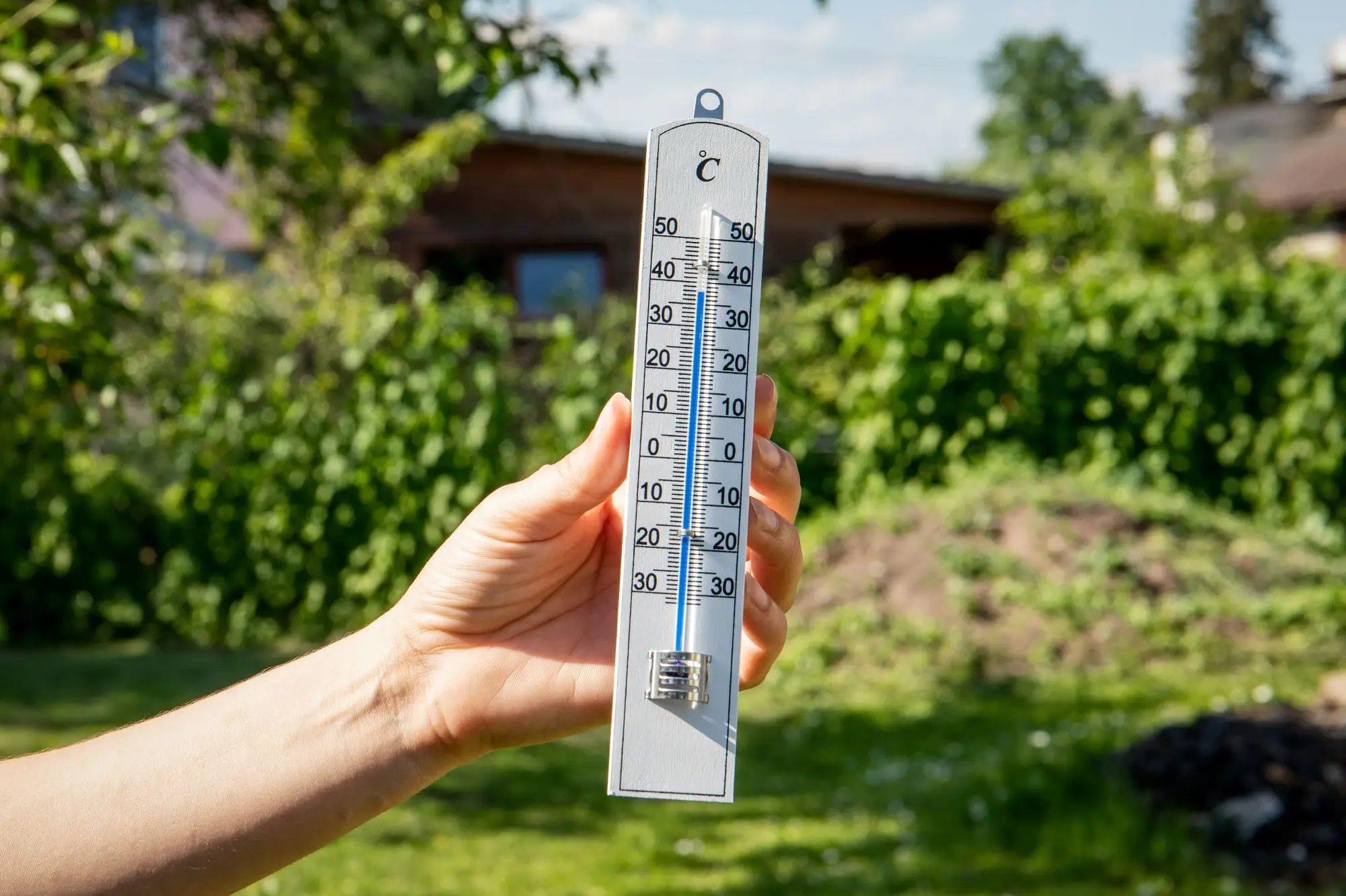 teploměr v ruce zobrazující teplotu 30 stupňů