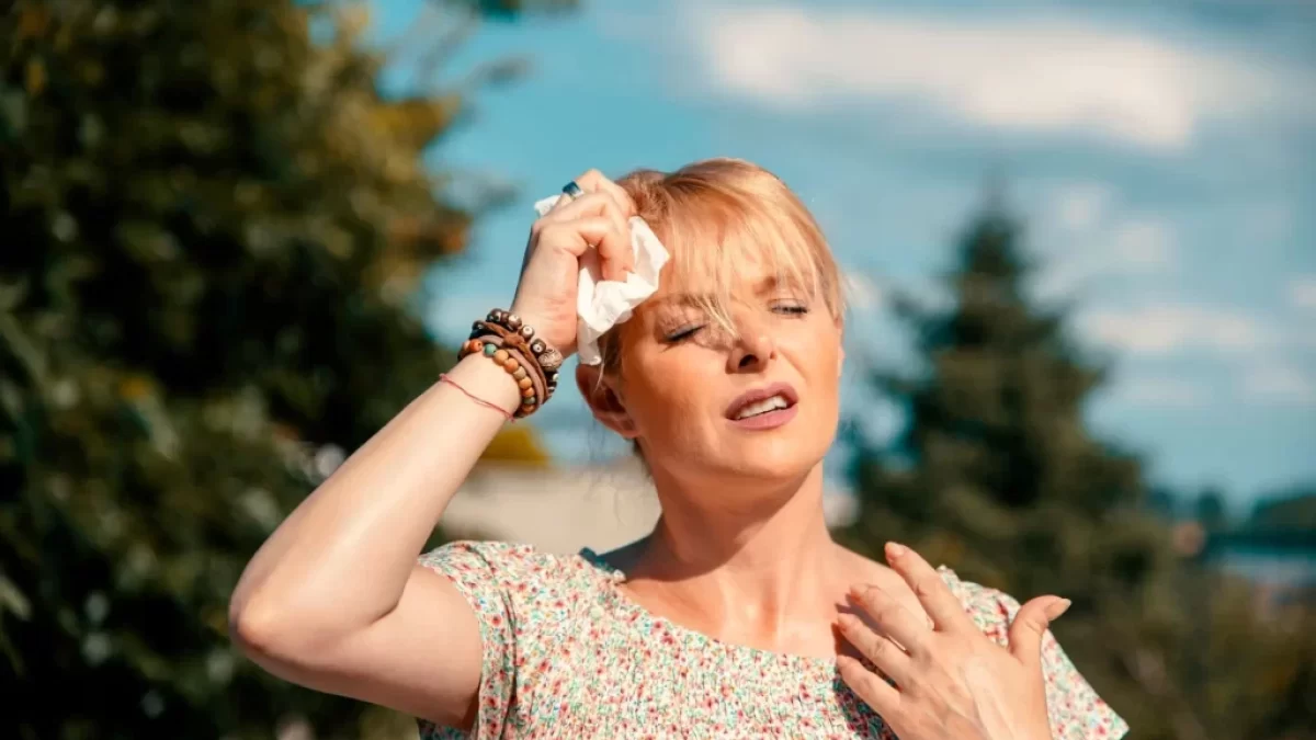 žena si v horku otírá obličej