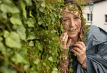 Mladá žena se zálibně dívá na plazivý břečťan u zdi