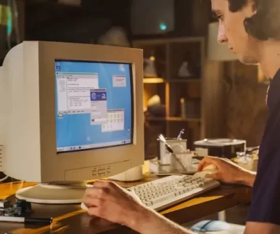 Mladý muž sedí za starou retro počítačovou sestavou a pracuje na ní