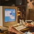Mladý muž sedí za starou retro počítačovou sestavou a pracuje na ní