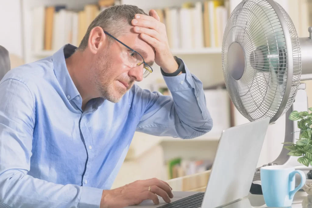 - SportDeník Muž u počítače trpí vedrem a chladí se ventilátorem.