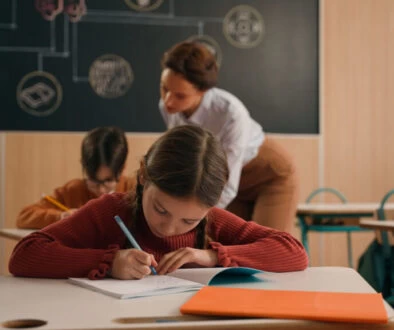 žákyně sedící ve třídě u stolu si dělá zápisky