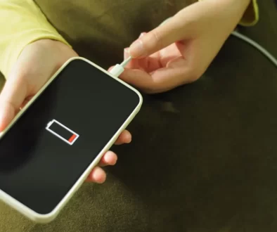 Ruce strkající koncovku nabíječky do vybitého telefonu
