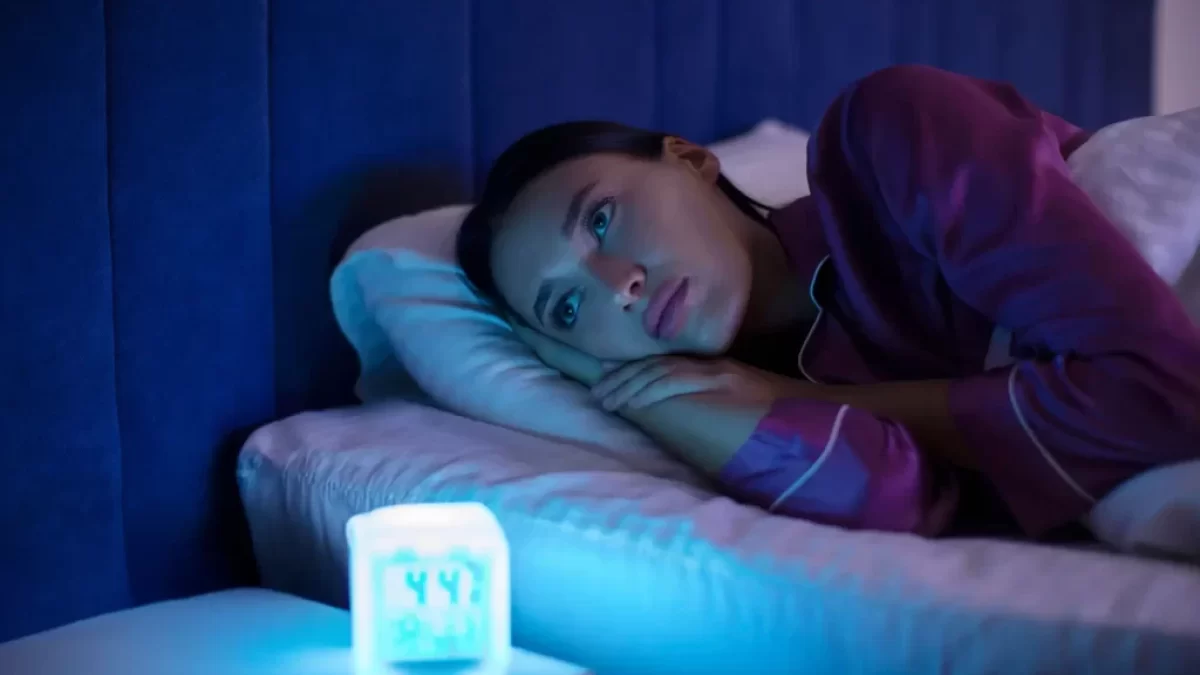 žena ležící na posteli u rozsvícené lampy