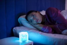 žena ležící na posteli u rozsvícené lampy