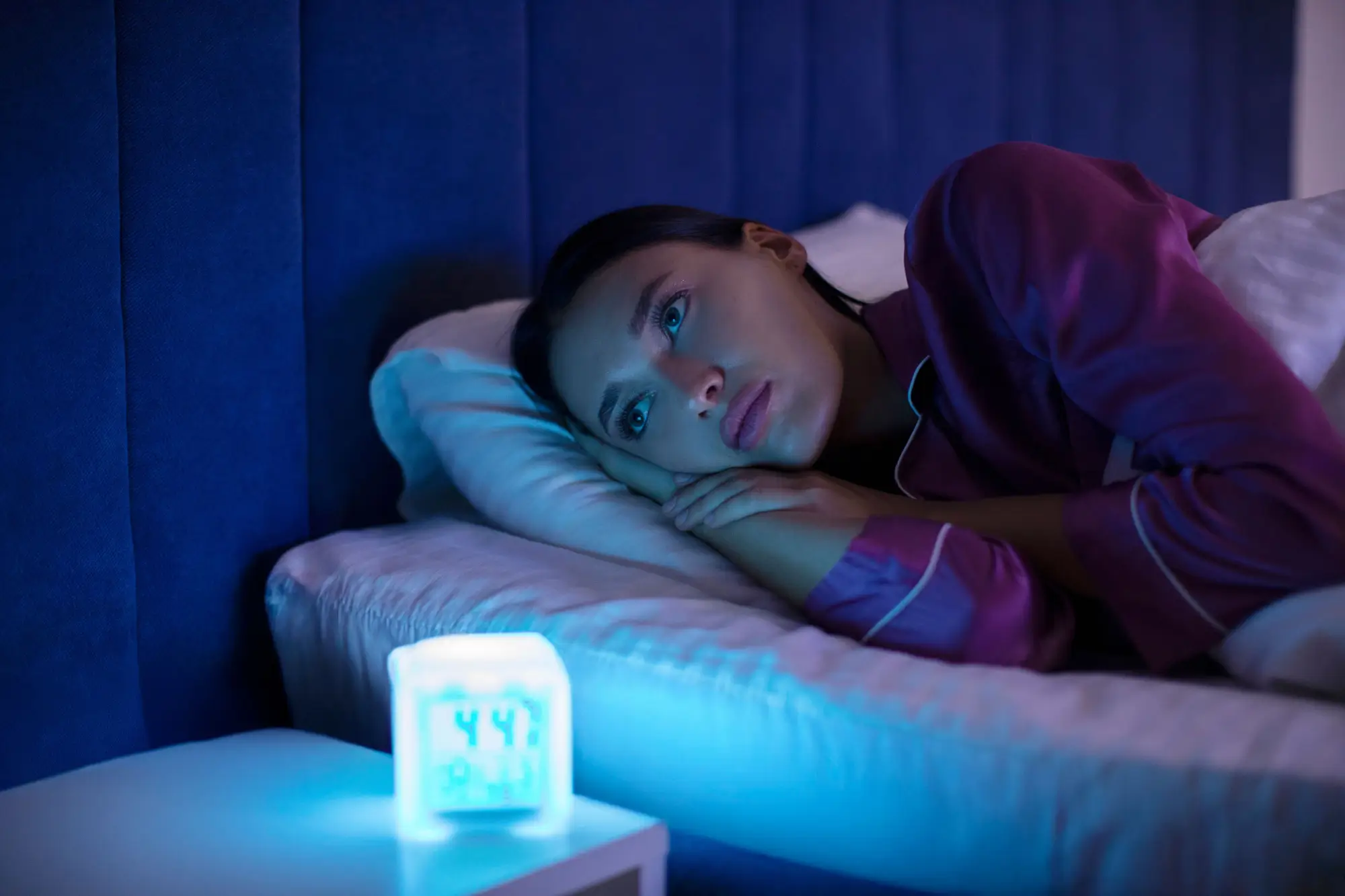 žena ležící na posteli u rozsvícené lampy