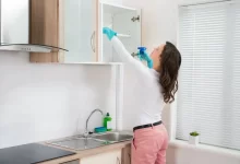 Žena čistí kuchyňskou skříňku s domácím přípravkem.