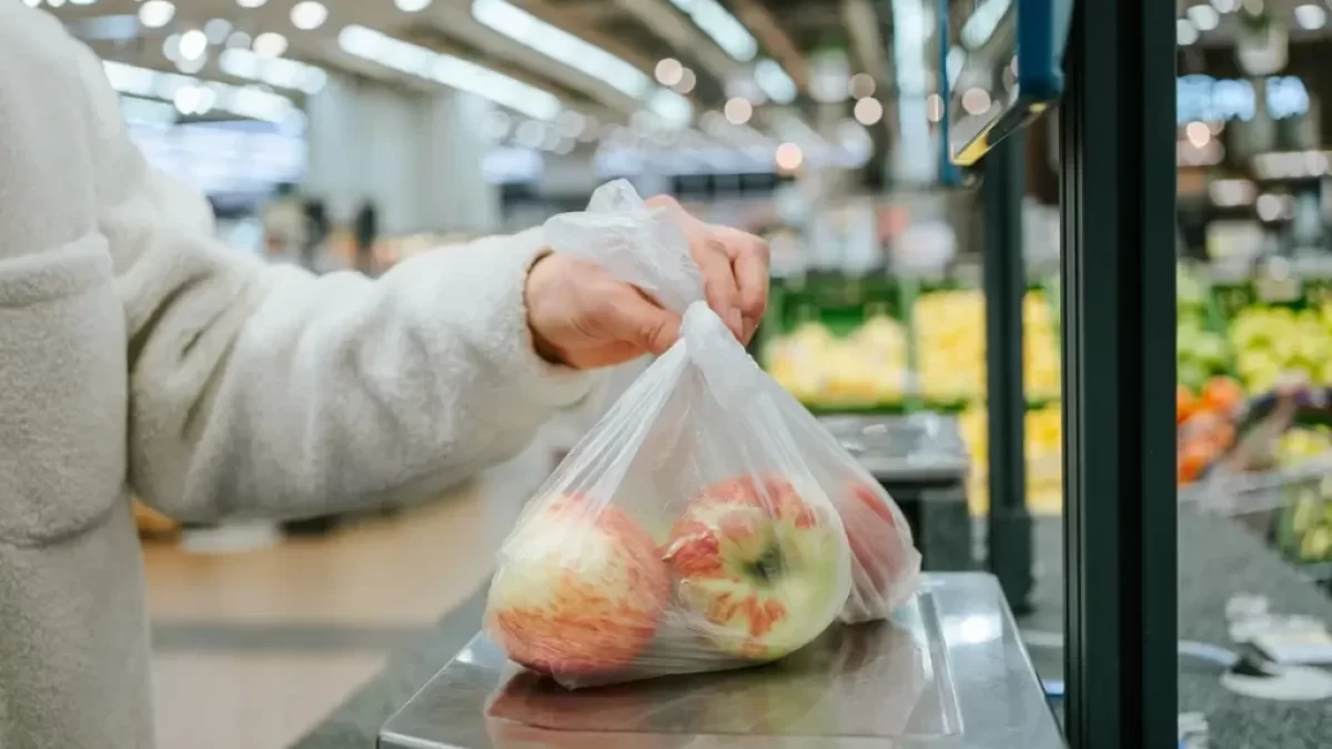 Ruka vkládající sáček s jablky na váhu samoobslužné pokladny