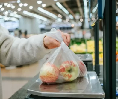 Ruka vkládající sáček s jablky na váhu samoobslužné pokladny