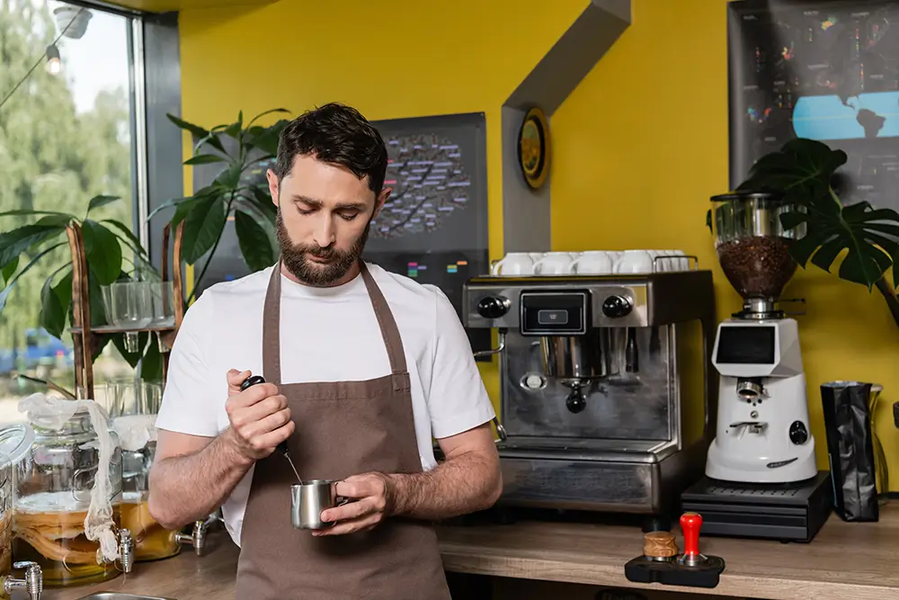 Nejprve je třeba vyšlehat mléko s espressem do pěny. - SportDeník barista šlehá méko