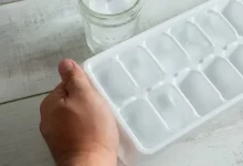 Plato s kostkami ledu a mužská ruka, která jej drží