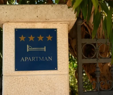 Sloupek domu s cedulkou, na které je napsáno "Apartmani"