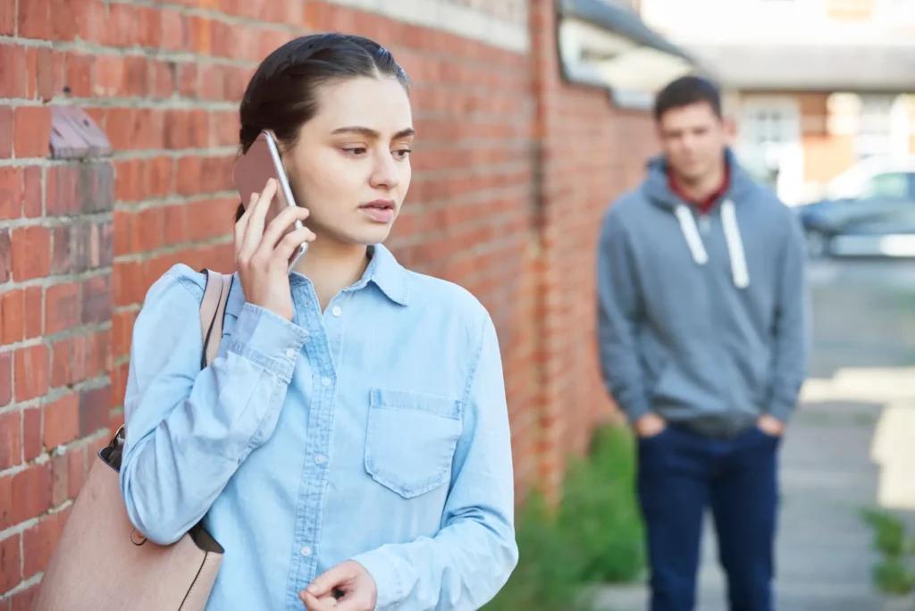 Muž pozorující telefonující mladou ženu na ulici