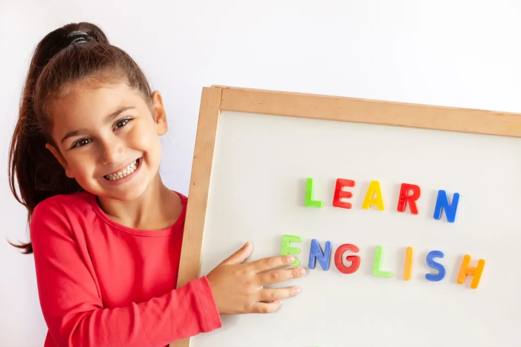Usměvavá dívka drží tabuli s nápisem Learn English.