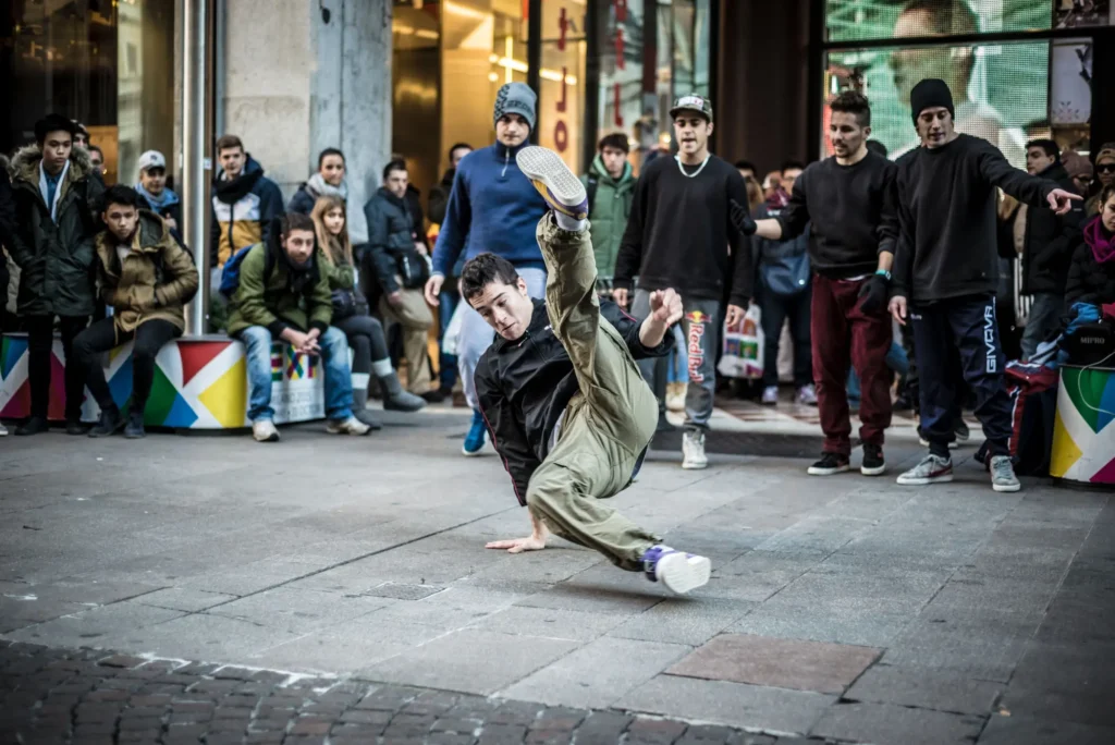 Mladý muž dělá breakdance na ulici a kolem stojí diváci