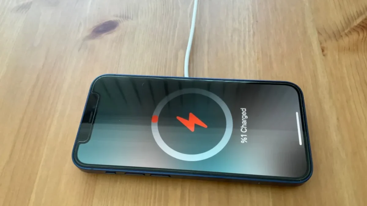Vybitý iPhone v nabíječce na stole