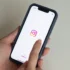 ženské ruce držící mobil s ikonou Instagramu na displeji
