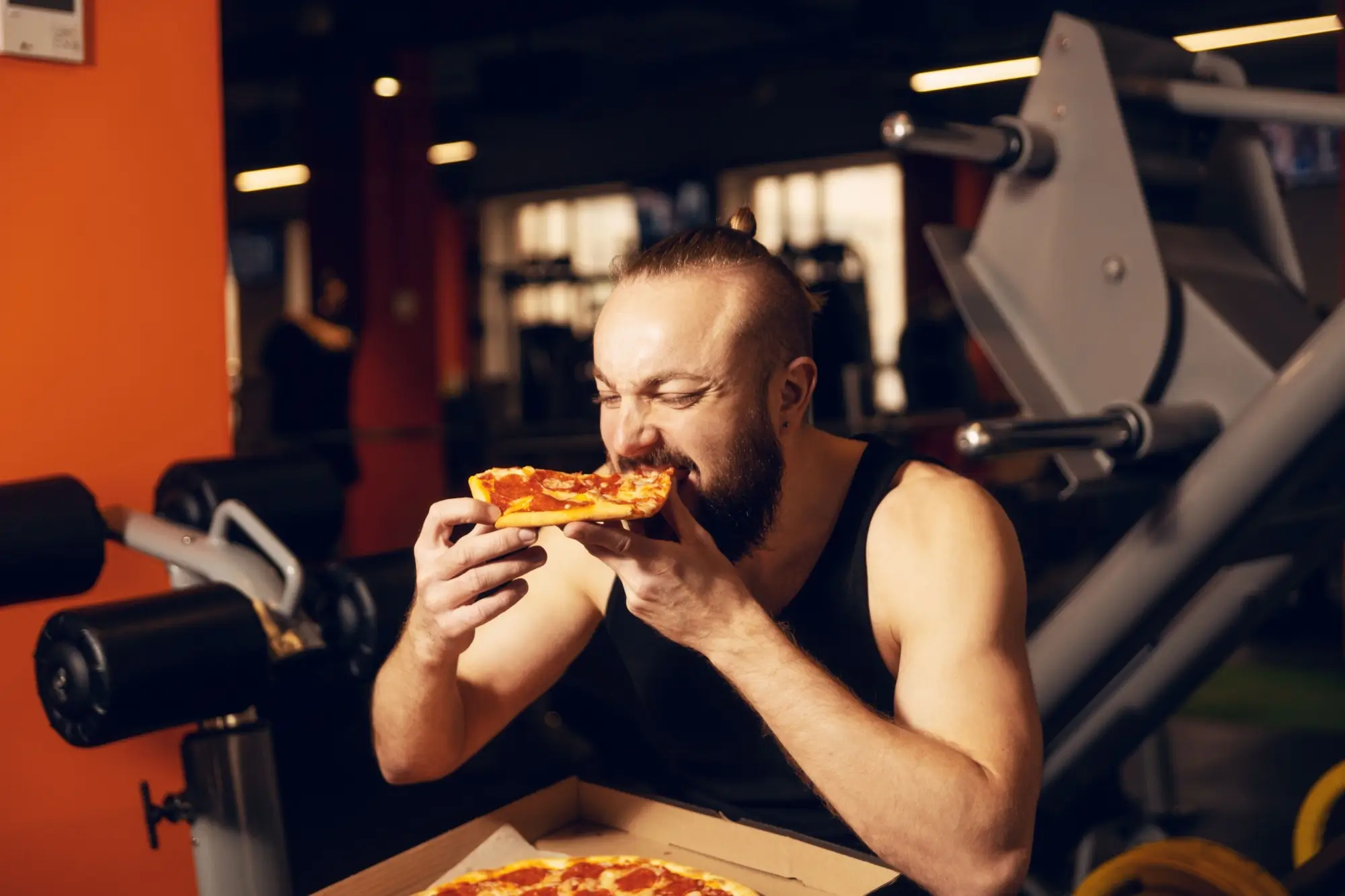 Shutterstock_2271759037 - SportDeník Muž jí v tělocvičně pizzu