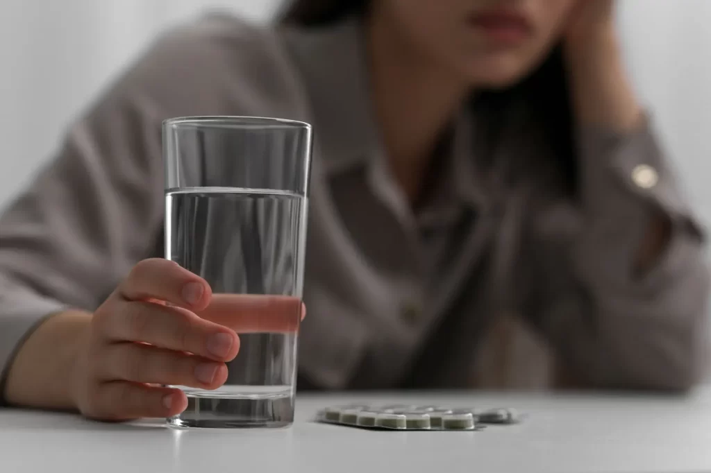 Žena se sklenicí vody a platem prášků