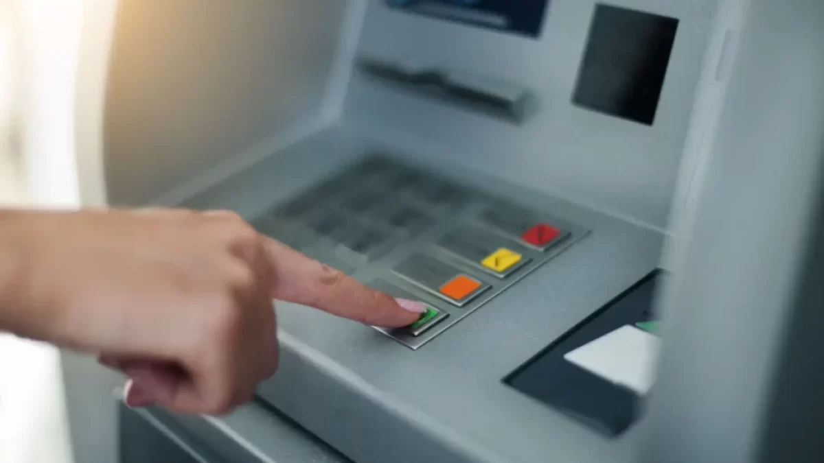 Ruka ženy mačkající tlačítka bankomatu