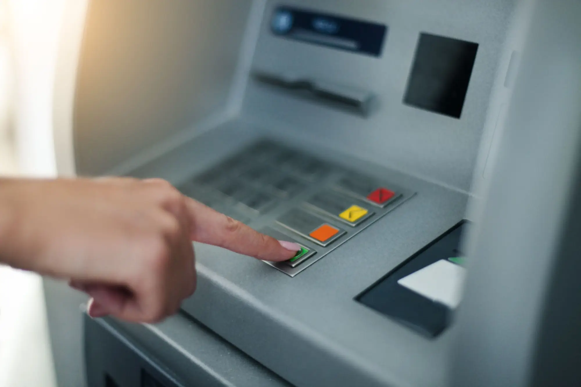 Ruka ženy mačkající tlačítka bankomatu
