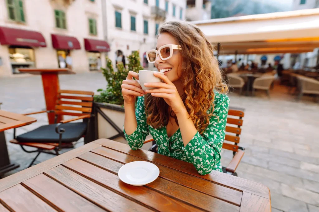 žena popíjející šálek kávy na zahrádce v restauraci