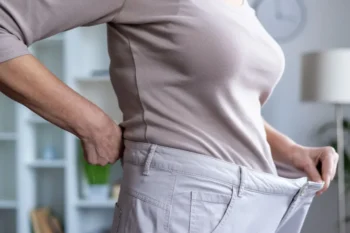 Žena ukazující, jak volné jí jsou kalhoty