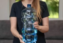 Žena drží velkou plastovou láhev s vodou.
