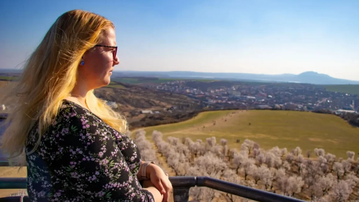 Žena stojící na vyhlídce a dívající se do dálky na krajinu.