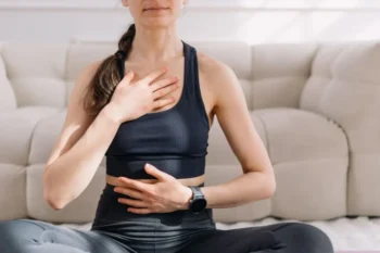 Žena se soustředí na hluboké břišní dýchání v klidné poloze.