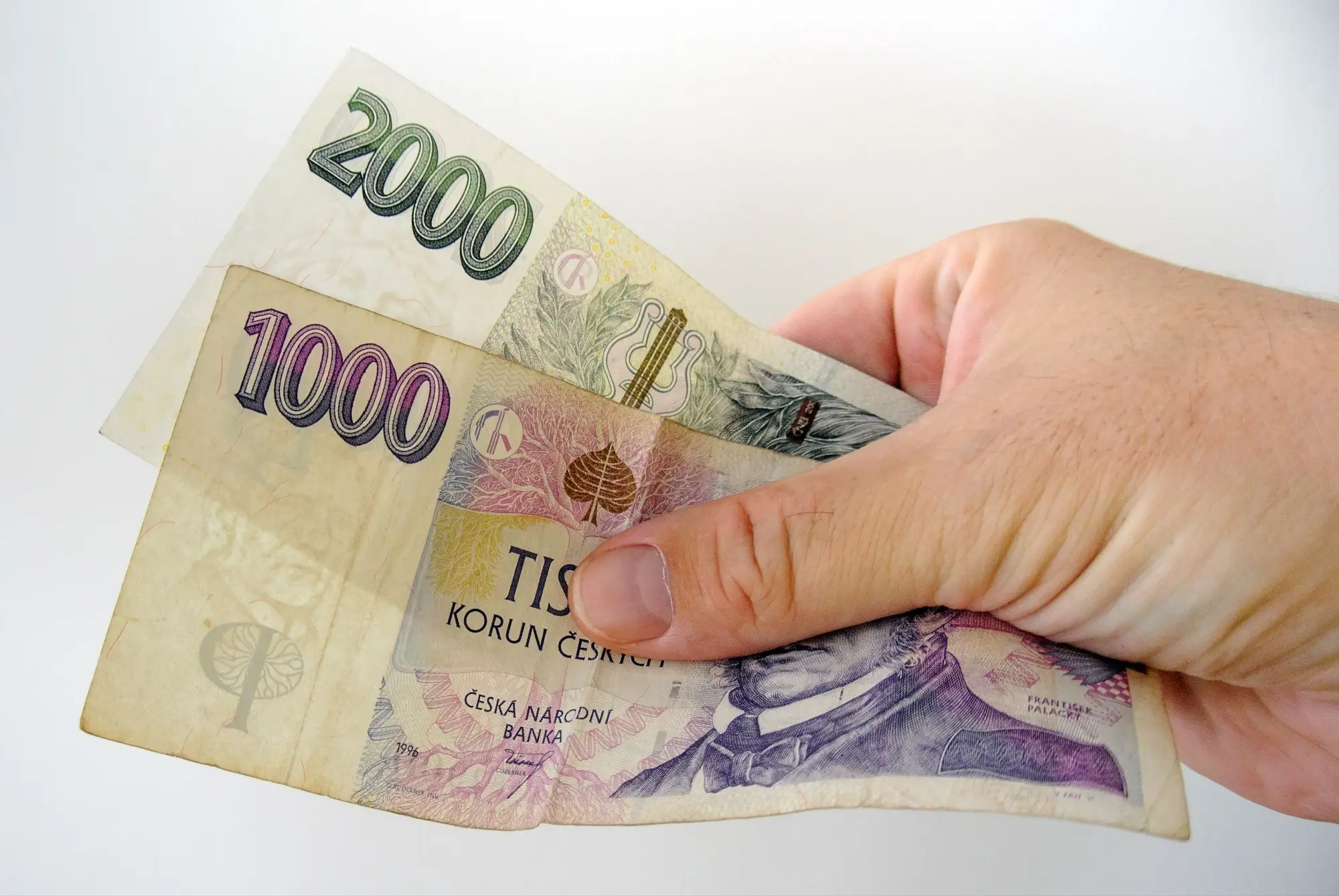 Ruka držící 3 000 Kč