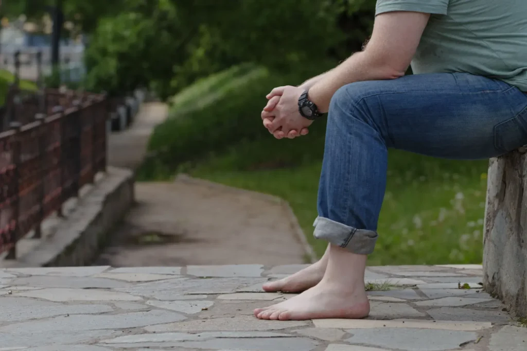 Muž s bosýma nohama sedí ve městě