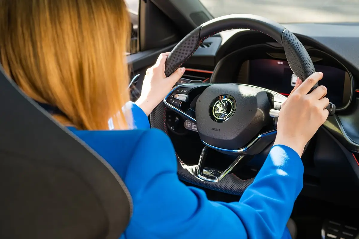 Žena v modrém saku řídí automobil značky Škoda 