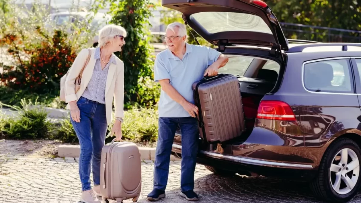 Usmívající se pár v seniorském věku ukládá kufry do auta