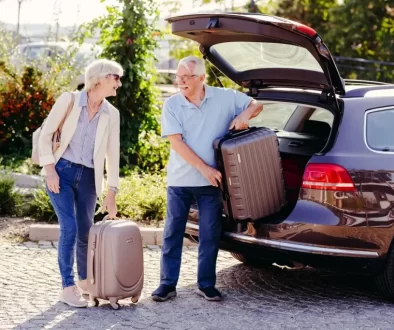 Usmívající se pár v seniorském věku ukládá kufry do auta