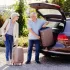 Usmívající se pár v seniorském věku ukládá kufry do auta