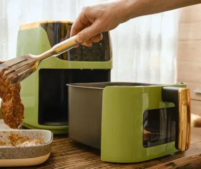 Ruka s kleštěmi, které nabírají plátek masa do horkovzdušné fritézy