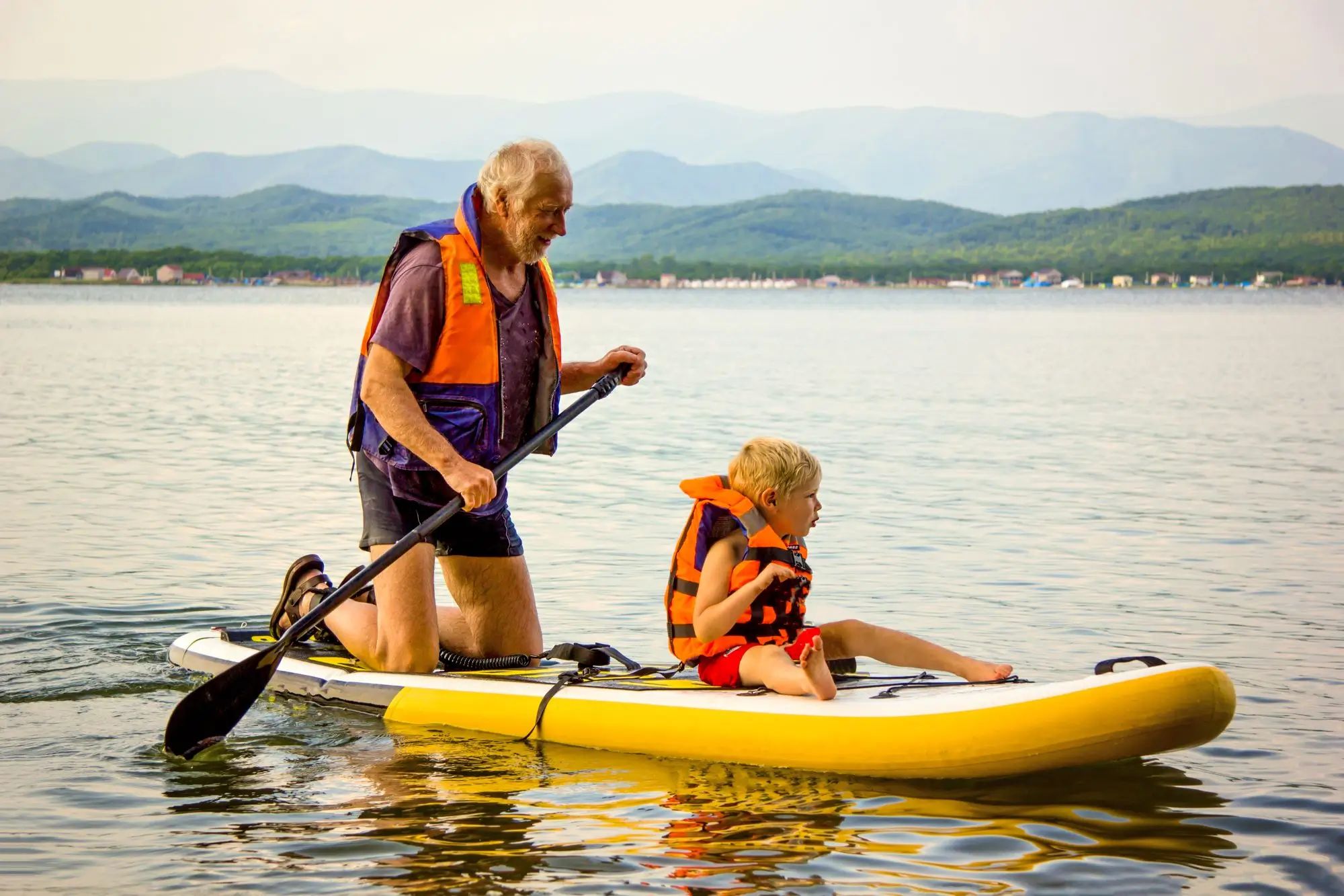 starší muž a dítě na paddleboardu